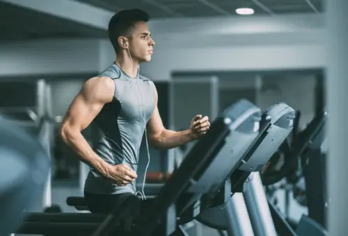 A focused cardio session in a modern gym—highlighting a fit man running on a treadmill, emphasizing endurance, fitness, and determination in an energized workout environment.